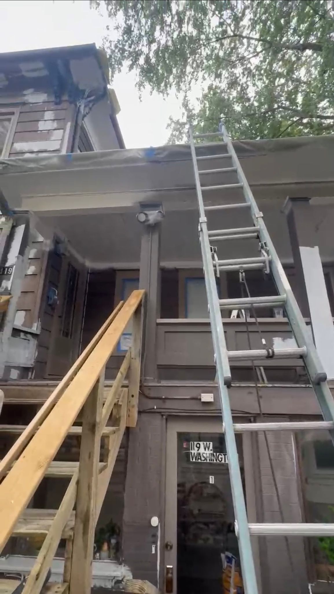 Painter working on gable of house exterior